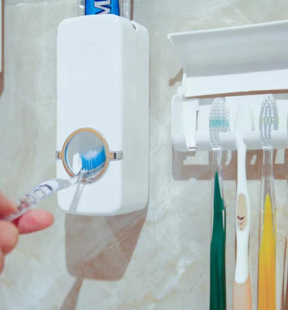 Wall mounted automatic toothpaste dispenser with toothbrush holder for clean bathroom use.